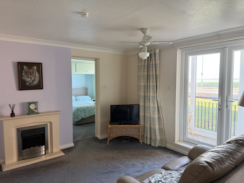 Lot: 131 - WELL PRESENTED GROUND FLOOR FLAT WITH SEA VIEWS - Living room with bedroom in background